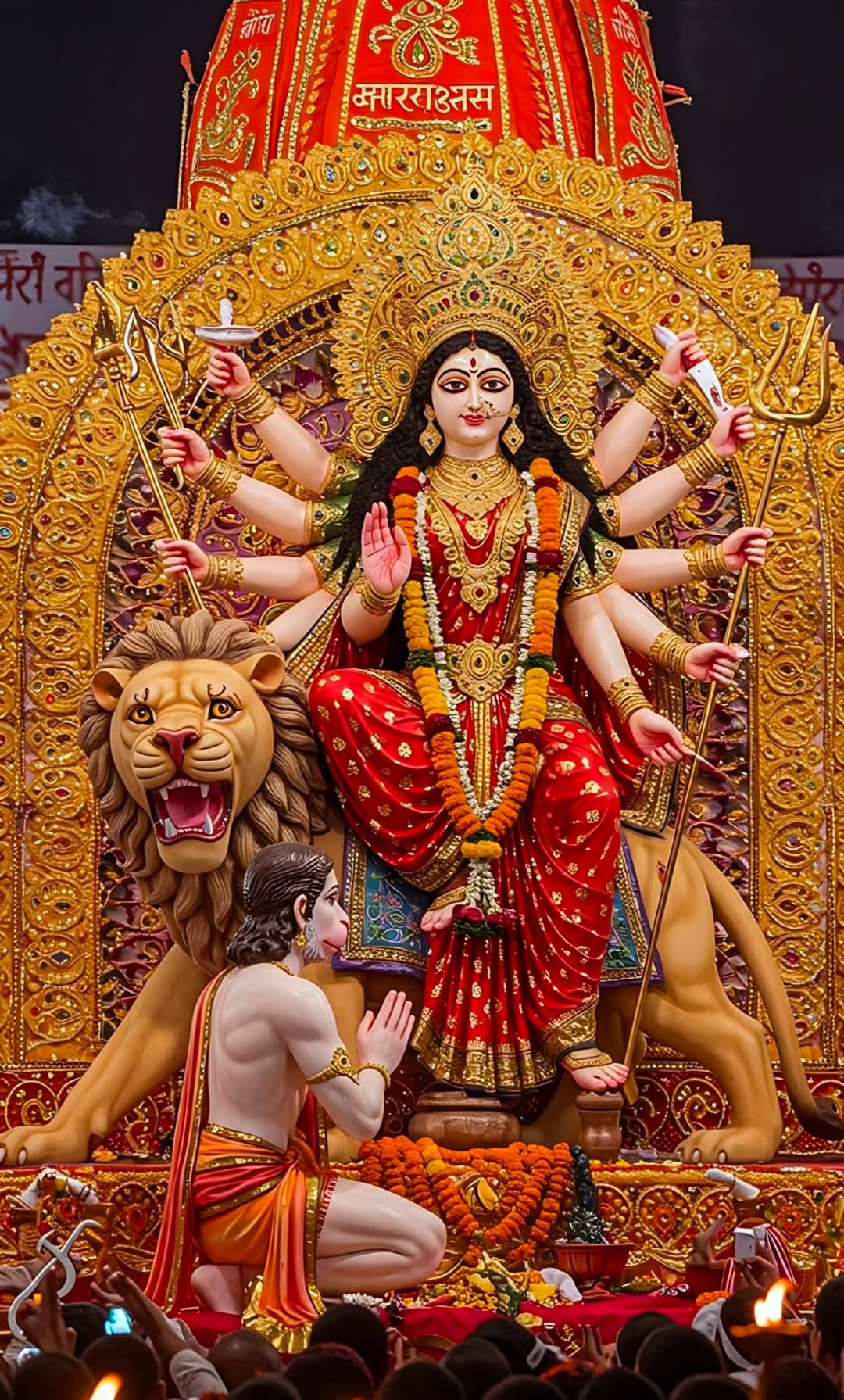 Durga in red saree with lion and Hanuman offering prayers.