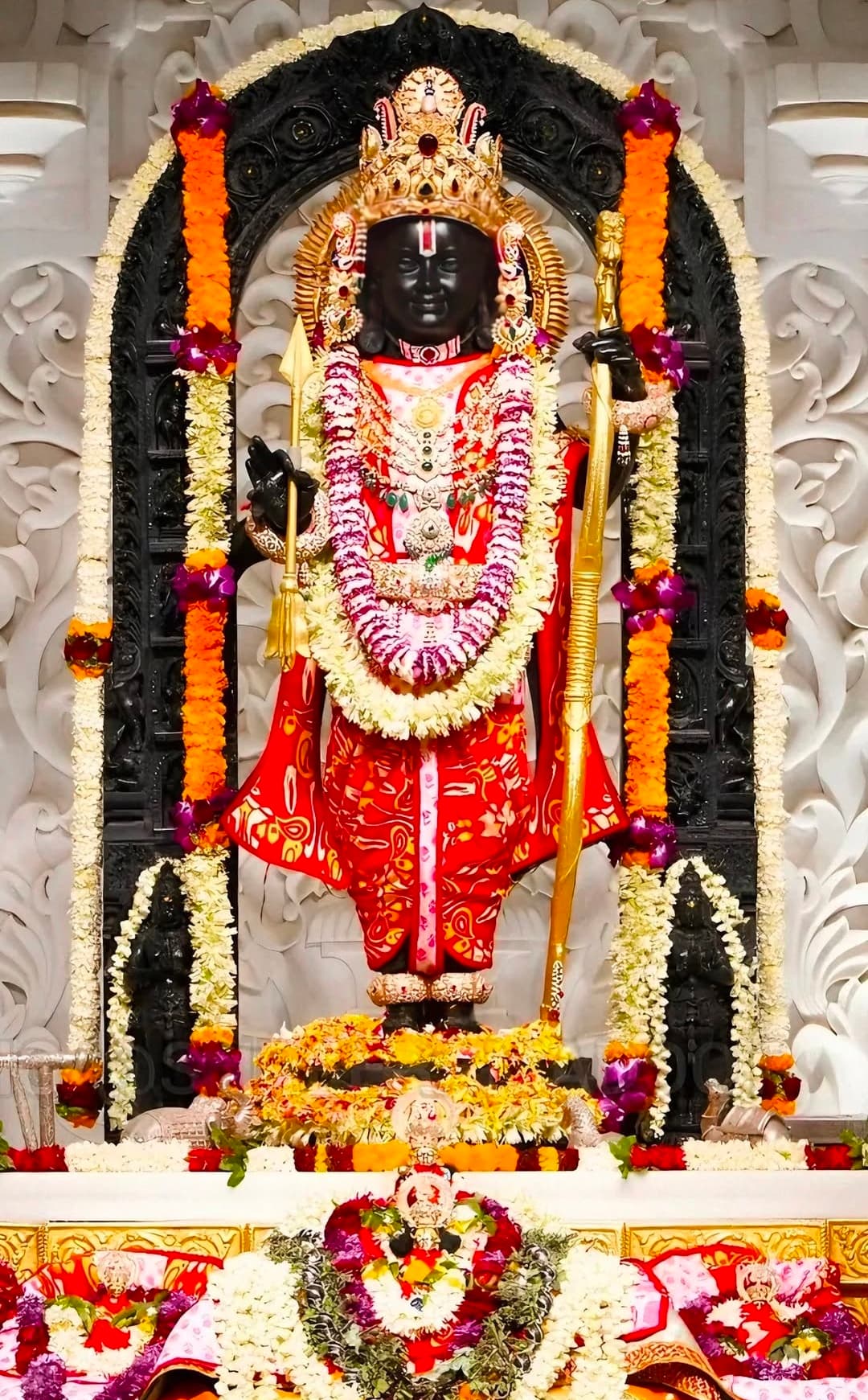 Idol of Lord Vitthal decorated with red attire and flower garlands in temple.